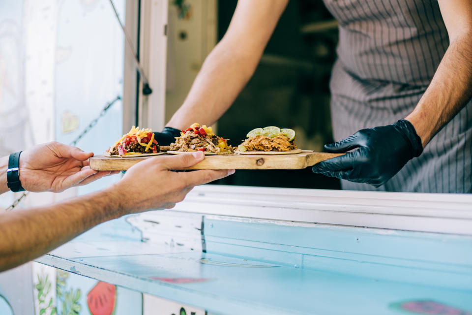 A tray of empanadas being handed to another person