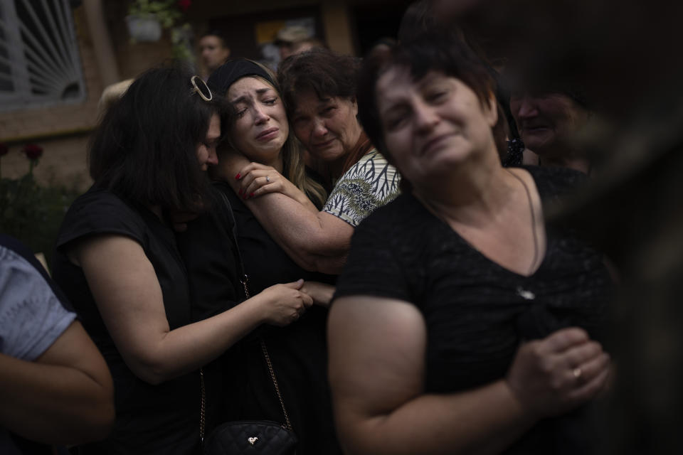 Anastasiia Okhrimenko, is comforted by relatives and friends as she mourns the loss of her husband, Yurii Stiahliuk, a Ukrainian serviceman who died in combat on Aug. 24 in Maryinka, Donetsk, during his funeral in Bucha, Ukraine, on Aug. 31, 2022. (AP Photo/Emilio Morenatti)