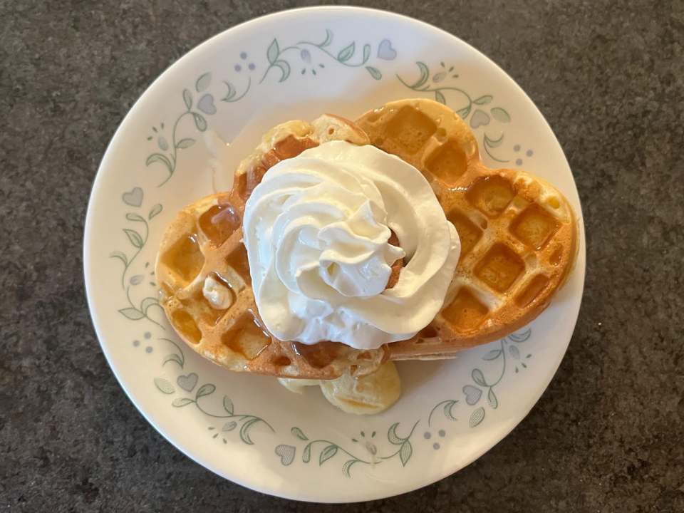 plate of two heart-shaped waffles topped with whipped cream