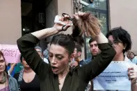 <p>Nasibe Samsaei, an Iranian woman living in Turkey, cuts her hair during a protest following the death of Mahsa Amini, outside the Iranian consulate in Istanbul, Turkey September 21, 2022. REUTERS/Murad Sezer</p> 
