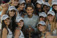 <p>Rafael Nadal displays his trophy, as he poses with the ball girls after winning the Madrid Open final against Kei Nishikori of Japan, in Madrid, May 11, 2014. (AP Photo/Andres Kudacki) </p>