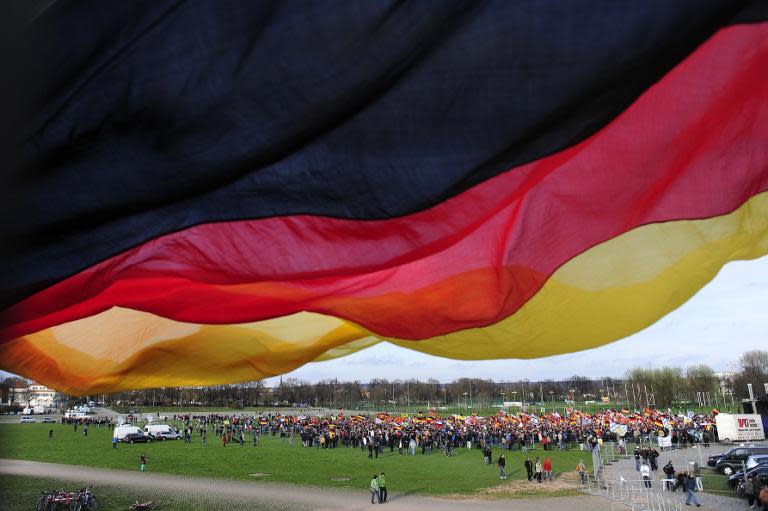 Sympathizers of German right-wing movement PEGIDA (Patriotic Europeans Against the Islamisation of the Occident) attend a rally as a German flag flys on April 13, 2015 in Dresden, south-eastern Germany