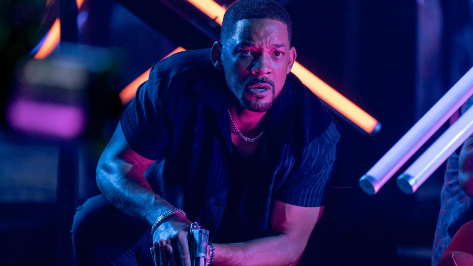 Will Smith crouched in action in a neon lit club while holding a gun in Bad Boys: Ride or Die.