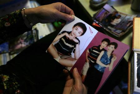 50 year-old Shi Hui shows pictures of her and her late son Tian Yao, born in August 1990 and died in January 2012 of lymphoma, at home in Beijing, December 26, 2013. REUTERS/Jason Lee