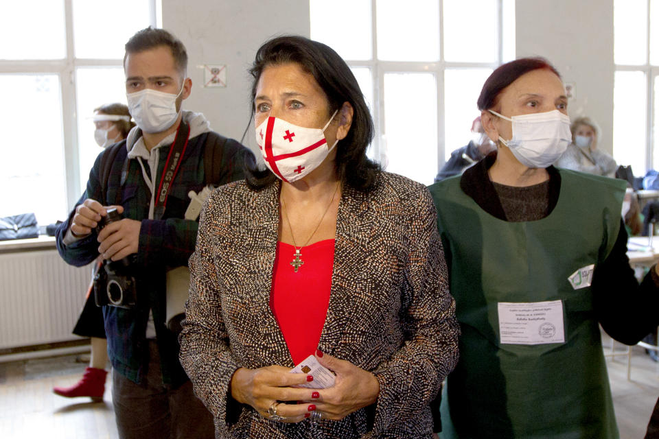 Georgia's President Salome Zurabishvili, center, wearing a face mask to help curb the spread of the coronavirus, speaks to journalists at a polling station during national municipal elections in Tbilisi, Georgia, Saturday, Oct. 2, 2021. Former President Mikheil Saakashvili was arrested after returning to Georgia, the government said Friday, a move that came as the ex-leader sought to mobilize supporters ahead of the national municipal elections seen as critical to the country's political makeup. The elections started Saturday. (AP Photo/Zurab Tsertsvadze)
