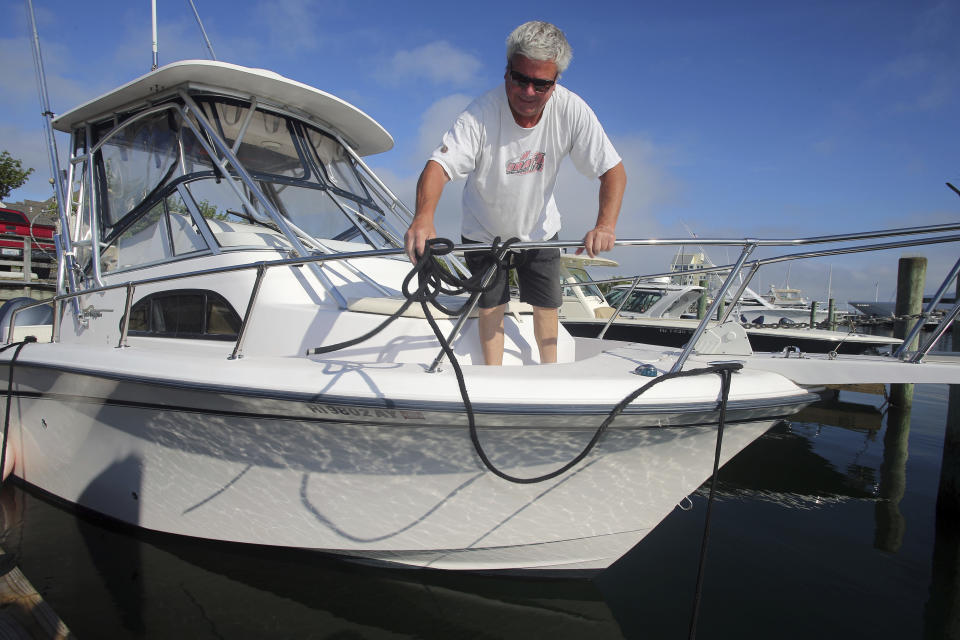 Rob Edwards, from Newport, R.I., adds extra lines to secure his boat at the Goat Island Marina, Saturday, Aug. 21, 2021, in Newport, R.I. New Englanders, bracing for their first direct hit by a hurricane in 30 years, are taking precautions as Tropical Storm Henri barrels toward the southern New England coast. (AP Photo/Stew Milne)