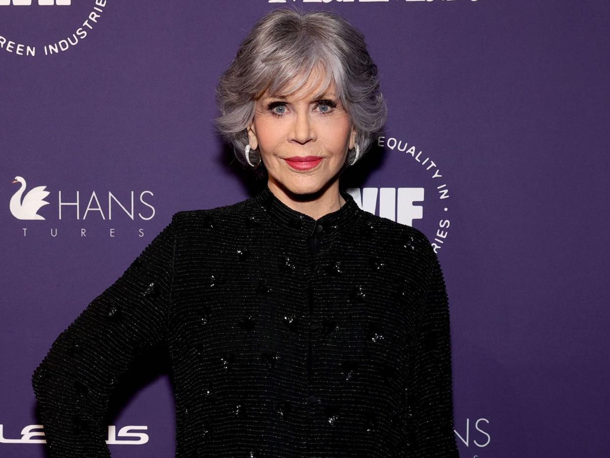 Jane Fonda poses for photos on the red carpet in a black gown.