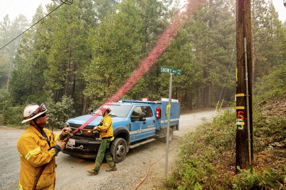 Pacific Gas & Electric firefighter Dave Ronco sprays retardant on a utility pole to protect infrastructure as the Mosquito Fire burns near Volcanoville in El Dorado County, Calif., on Friday, Sept. 9, 2022. (AP Photo/Noah Berger)