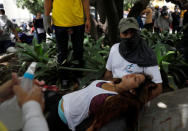 A woman is helped by demonstrators during a rally against President Nicolas Maduro in Caracas, Venezuela May 24, 2017. REUTERS/Carlos Garcia Rawlins