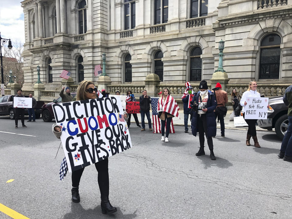 A woman holds a sign expressing her displeasure with New York Governor Andrew Cuomo at a noisy rally against the Governor's social distancing restrictions, outside the State Capitol, Wednesday, April 22, 2020 in Albany, N.Y. Similar "Operation Gridlock" protests publicized on social media have been happening across the country, with organizers calling the shutdown an extreme example of governmental overreach. (AP Photo/Mary Esch)