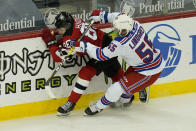 New York Rangers' Ryan Lindgren, right, pushes New Jersey Devils' Jack Hughes into the boards during the first period of the NHL hockey game in Newark, N.J., Sunday, April 18, 2021. (AP Photo/Seth Wenig)