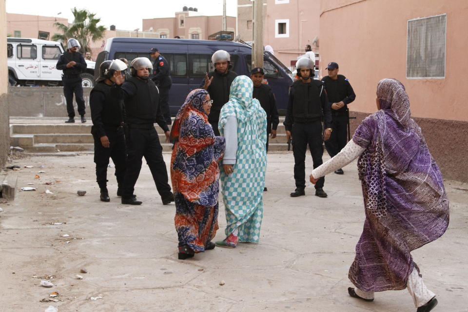 FILE - In this photo taken Tuesday, Dec. 10, 2013, Western Saharan women confront riot police in Laayoune, the capital of the disputed territory of the Western Sahara. The Moroccan military has intervened in a U.N.-patrolled border zone in the disputed Western Sahara to clear a key road it said was being blockaded for weeks by supporters of the pro-independence Polisario Front. Moroccan forces set up a security cordon overnight in the Guerguerat buffer zone on Western Sahara's southern border with Mauritania, "in order to secure the flow of goods and people through this axis," (AP Photos/Paul Schemm, File)