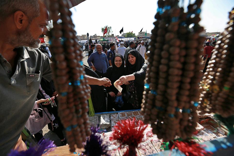 Iranian Shiite pilgrims shop for religious items outside the holy shrine of Imam Hussein ahead of the Arbaeen festival in Karbala, Iraq, Friday, Oct. 18, 2019. The holiday marks the end of the forty day mourning period after the anniversary of the martyrdom of Imam Hussein, the Prophet Muhammad's grandson in the 7th century. (AP Photo/Hadi Mizban)