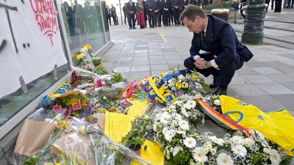 Swedish Prime Minister Ulf Kristersson looking at flowers in Brussels laid to commemorate the victims of the attack