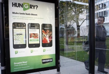 A man looks at an ad as he walks past a bus stop near Groupon Inc corporate headquarters in Chicago, Illinois, November 4, 2011. REUTERS/Frank Polich