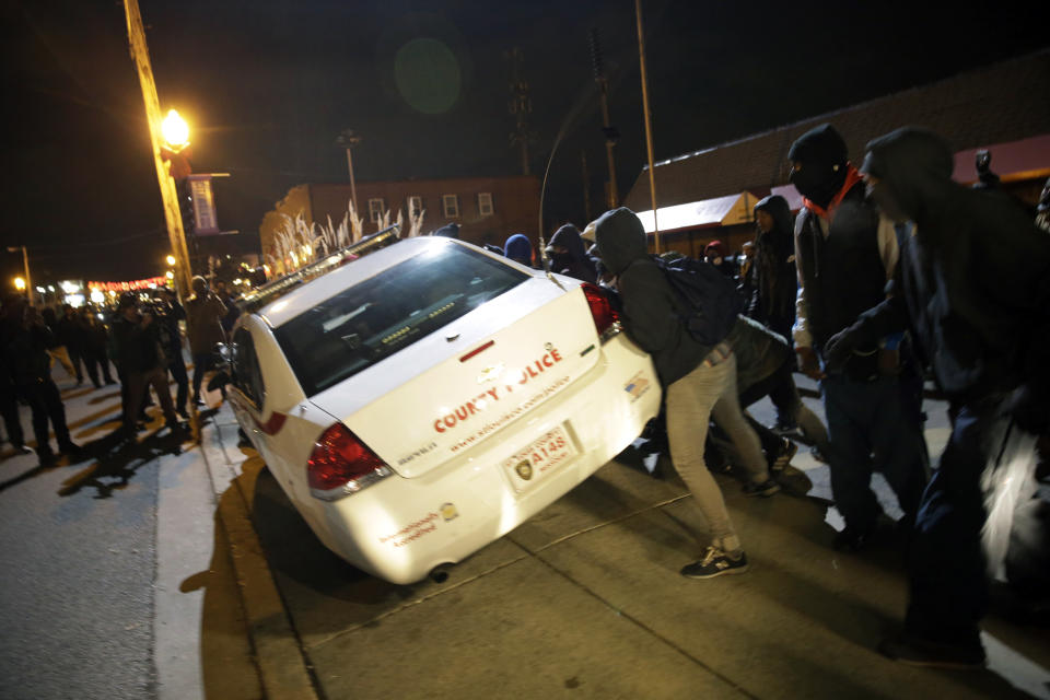 <p>Protesters shove a police car after the announcement of the grand jury decision not to indict police officer Darren Wilson in the fatal shooting of Michael Brown, an unarmed black 18-year-old, Monday, Nov. 24, 2014, in Ferguson, Mo. (AP Photo/David Goldman) </p>