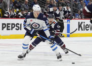 Winnipeg Jets center Morgan Barron, left, drives past Colorado Avalanche center Andrew Cogliano, center right, in the second period of an NHL hockey game Saturday, April 13, 2024, in Denver. (AP Photo/David Zalubowski)