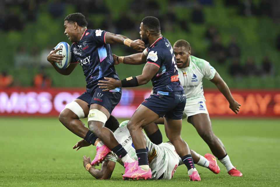 Angelo Smith of the Rebels, left, breaks a tackle from a Drua defender during their Super Rugby Pacific Round 7 match in Melbourne, Friday, April 5, 2024. (James Ross/AAP Image via AP)