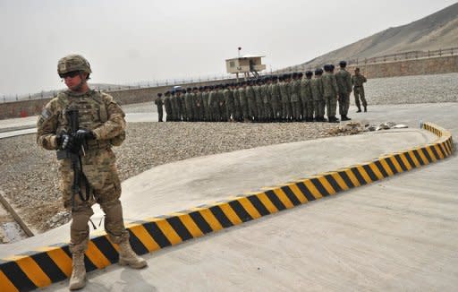 A US soldier stands guard as Afghanistan's Public Protection Forces (APPF) soldiers stand to attention on a base on the outskirts of Kabul on March 15, 2012. Teh US is seeking to ensure any remaining soldiers in Afghanistan will have immunity from prosecution in local courts