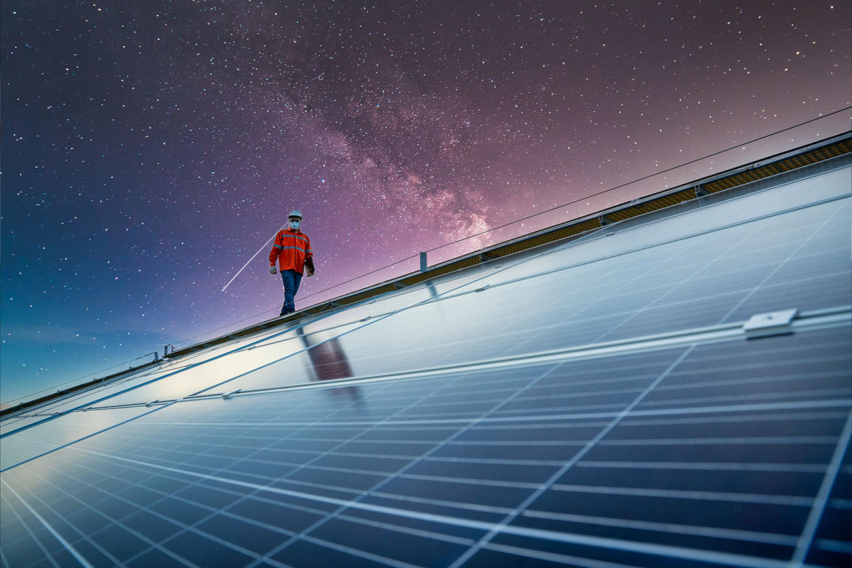 Engineer working on checking equipment in solar power plant with galaxies in the background Getty Images/Pramote Polyamate