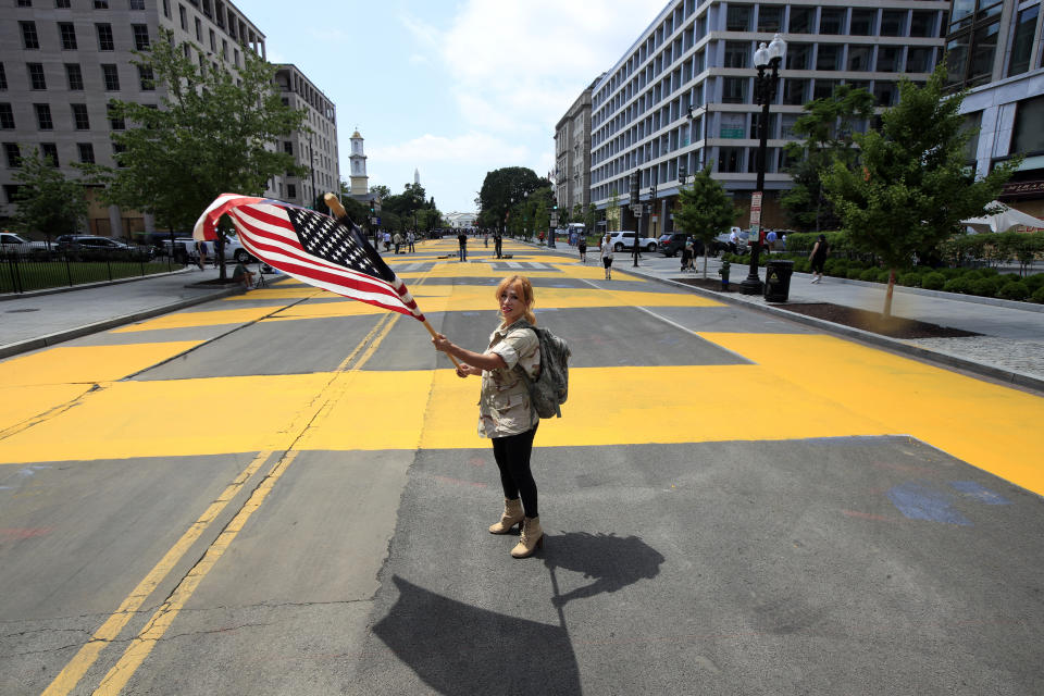 Beth Shafa waves an American Flag near the White House, Friday, June 5, 2020, in Washington. City workers and activists painted the words Black Lives Matter in enormous bright yellow letters on the street leading to the White House, a highly visible sign of the District of Columbia's embrace of a protest movement that has put it at odds with President Donald Trump. (AP Photo/Manuel Balce Ceneta)