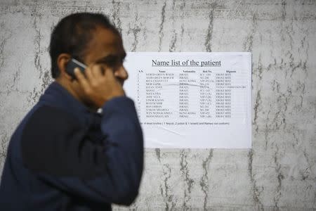 A man from a local travel agency talks to his friend on a mobile phone as he reads out names from a list showing the names of patients who were rescued from the recent avalanches and undergoing treatment at the Army hospital in Kathmandu October 16, 2014. REUTERS/Navesh Chitrakar