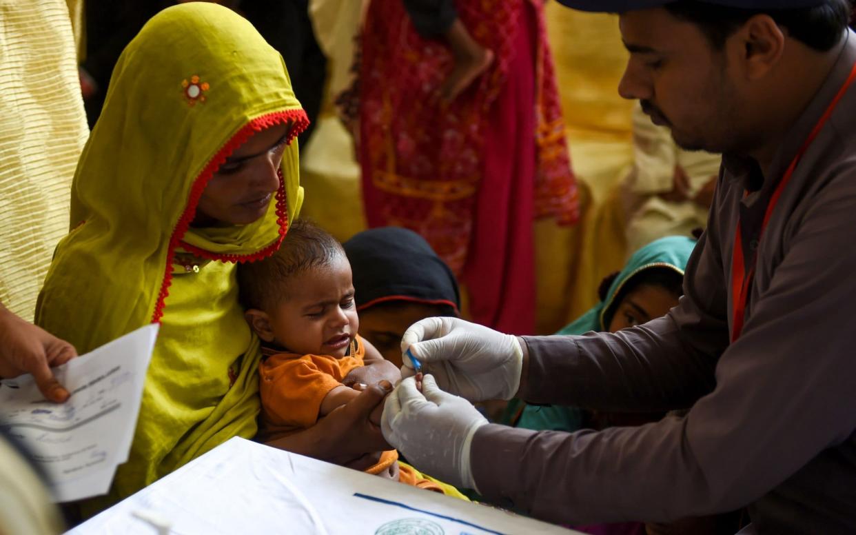 A paramedic takes a blood sample from a baby for an HIV test in the district of Larkana - AFP