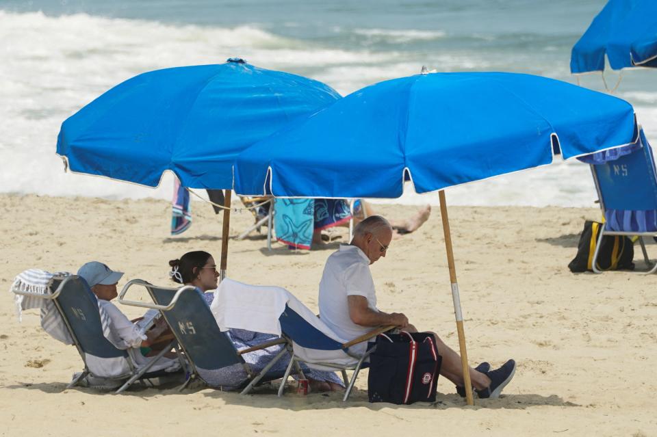 President Joe Biden, granddaughter Naomi and first lady Jill Biden sit under umbrellas at Rehoboth Beach, Delaware (REUTERS)