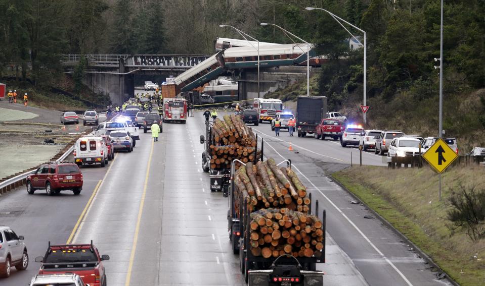 Logging trucks remain stopped just before where cars from an Amtrak train lay spilled onto Interstate 5 below alongside smashed vehicles as some train cars remain on the tracks above, in DuPont, Wash. The Amtrak train making the first-ever run along a faster new route hurtled off the overpass Monday near Tacoma and spilled some of its cars onto the highway below, killing some people, authorities said. Seventy-eight passengers and five crew members were aboard when the train moving at more than 80 mph derailed about 40 miles south of Seattle before 8 a.m., Amtrak said — Shutterstock/AP