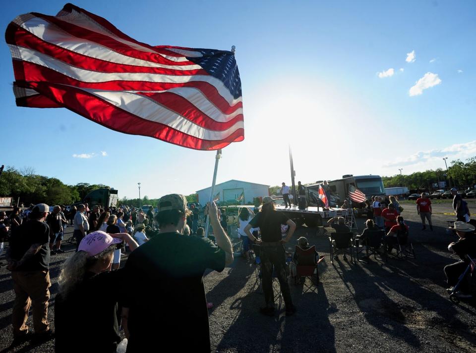 Steve and Krista Peiffer of Hedgesville, W.Va., fly an American flag Wednesday evening during the return of The People's Convoy at the Hagerstown Speedway. The two were listening to speeches at a 6 p.m. rally.