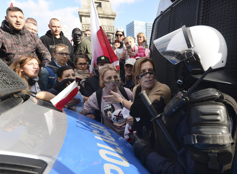 Polish police face protesters, angry over new restrictions aimed at fighting the coronavirus pandemic, in Warsaw, Poland, Saturday, Oct. 24, 2020. The protesters included entrepreneurs, far-right politicians, football fans and vaccine opponents. The clashes come amid rising social tensions and as new restrictions just short of a full lockdown took effect Saturday. (AP Photo/Czarek Sokolowski)