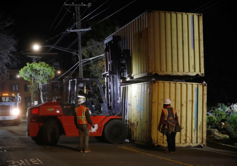 Crews install shipping containers around the perimeter of People’s Park in Berkeley, Calif., on Thursday, Jan. 4, 2024. Police officers in riot gear removed activists and crews put in shipping containers to wall off the historic park overnight as the University of California, Berkeley waits for a court ruling it hopes will allow it to build much-needed student housing. (Jane Tyska/Bay Area News Group via AP)