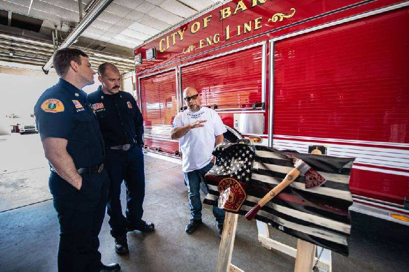 Wood sculptor Rob Rivera of Apple Valley, right, created a handcrafted flag for Barstow Fire Chief Nick DiNapoli and his team of firefighters.
