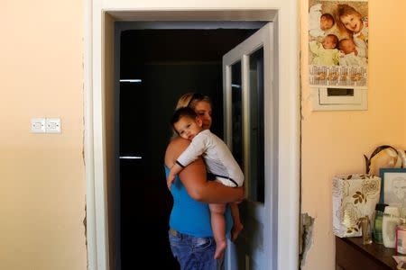 Nikoletta Futo holds one of her triplet sons in the doorway to their darkened bedroom in Kanjiza, Serbia, July 7, 2017, after a grant from the Hungarian government enabled the family of six to purchase a house on the outskirts of the town. REUTERS/Bernadett Szabo