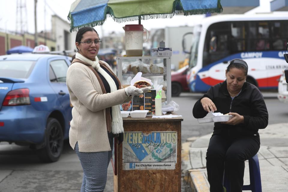 In this June 12, 2019 photo, Venezuelan arepa's vendor Yuleiny Mendoza pose for a photo at her arepa stand at a street corner in Lima, Peru. When Venezuela was one of Latin America's most prosperous countries, the poor and the wealthy would typically eat two or three arepas a day. (AP Photo/Martin Mejia)