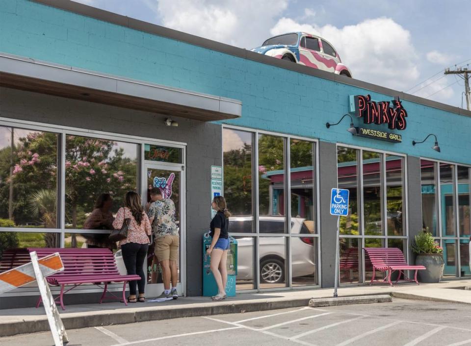 A family peers into the windows at Pinky’s Westside Grill after they found out they were closed for filming in Charlotte, N.C., on Thursday, July 13, 2023.