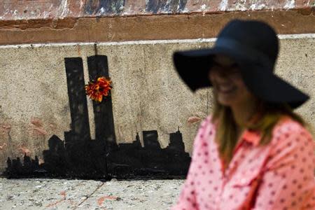 A woman poses for a picture next to new artwork by British graffiti artist Banksy at Lower Manhattan in New York, October 15, 2013. REUTERS/Eduardo Munoz