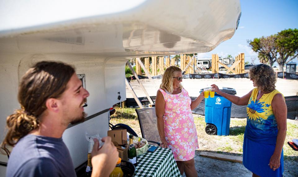 Debi Szekely shares a toast with neighbor, Christal Shola after a groundbreaking for her new home on Hibiscus Drive on Fort Myers Beach on Friday, Sept. 8, 2023. Here home was destroyed in Hurricane Ian last year. Homebound is building a new home on the property. On the left is Szekely's son Ben.