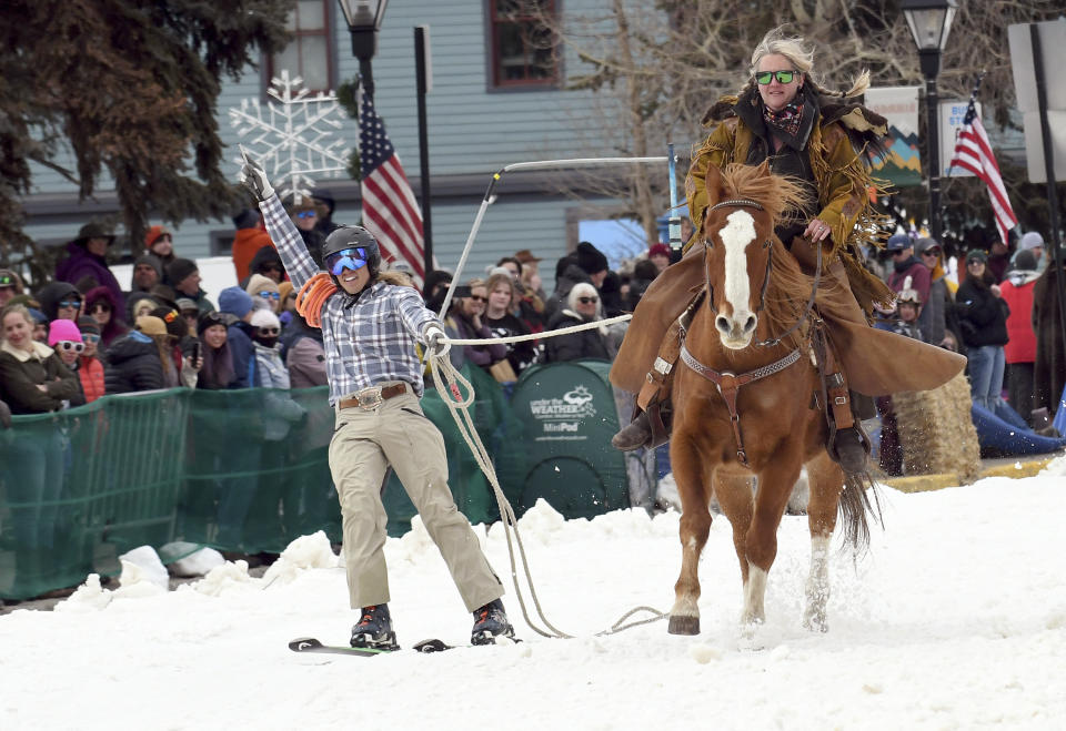 A skijoring team competes in Leadville, Colo., on Saturday, March 2, 2024. Skijoring draws its name from the Norwegian word skikjoring, meaning "ski driving." It started as a practical mode of transportation in Scandinavia and became popular in the Alps around 1900. Today's sport features horses at full gallop towing skiers by rope over jumps and around obstacles as they try to lance suspended hoops with a baton, typically a ski pole that's cut in half. (AP Photo/Thomas Peipert)