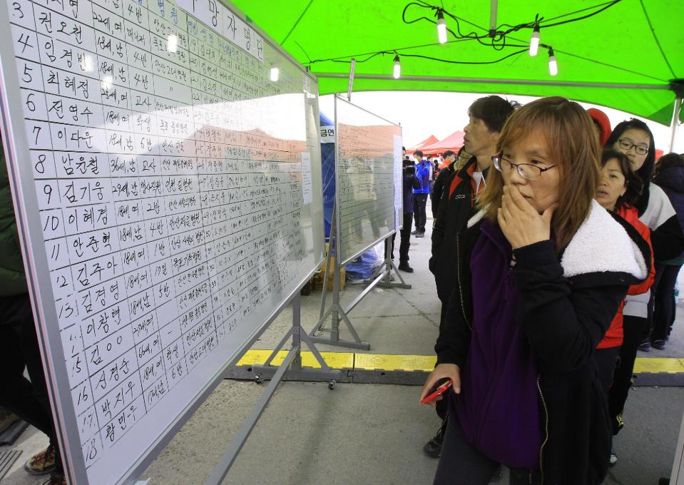 A relative of a passenger aboard the sunken ferry Sewol watches the official list of the dead victims at a port in Jindo, South Korea, Monday, April 21, 2014. Divers continued the grim work of recovering bodies from inside the sunken South Korean ferry in the water off the southern coast Monday, as a newly released transcript showed the ship was crippled by confusion and indecision well after it began listing. The transcript suggests that the chaos may have added to a death toll that could eventually exceed 300. (AP Photo/Ahn Young-joon)