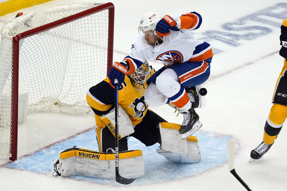 New York Islanders' Leo Komarov (47) leaps but can't get out of the way of a shot in front of Pittsburgh Penguins goaltender Tristan Jarry during the third period in Game 1 of an NHL hockey Stanley Cup first-round playoff series in Pittsburgh, Sunday, May 16, 2021. (AP Photo/Gene J. Puskar)