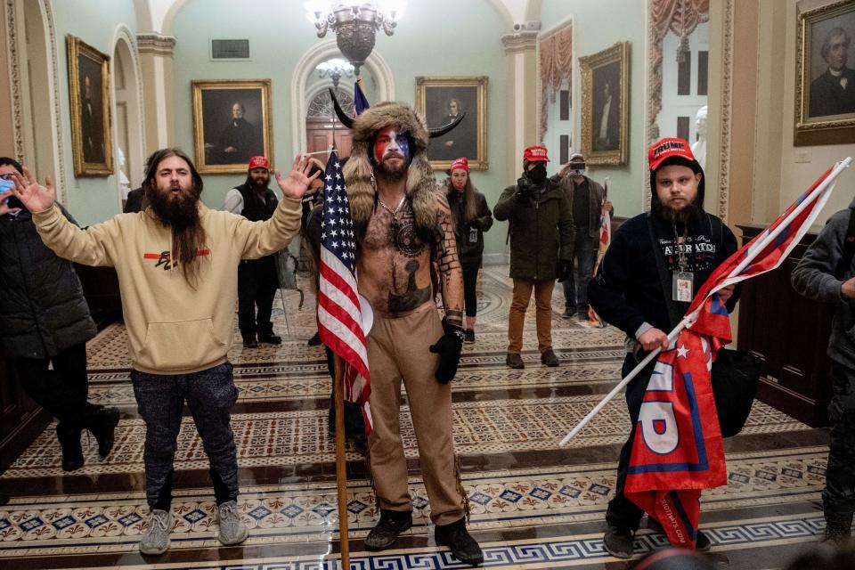 El hombre a la derecha en la foto,con gorra y bandera de Trump, ha sido despedido de su empleo en la empresa Navistar de Maryland. El individuo, quien no ha sido identificado públicamente, participó en la turba que asaltó al Capitolio usando la identificación de su empresa colgada al cuello, como puede apreciarse en la imagen. SAUL LOEB/AFP via Getty Images