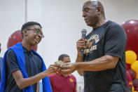 Kanga Gwanyama, 13, left, accepts a $5,000 gift from Washington Commanders part-owner Magic Johnson at the Boys & Girls Club of Greater Washington, Thursday, Sept. 7, 2023, in Washington. (AP Photo/Alex Brandon)