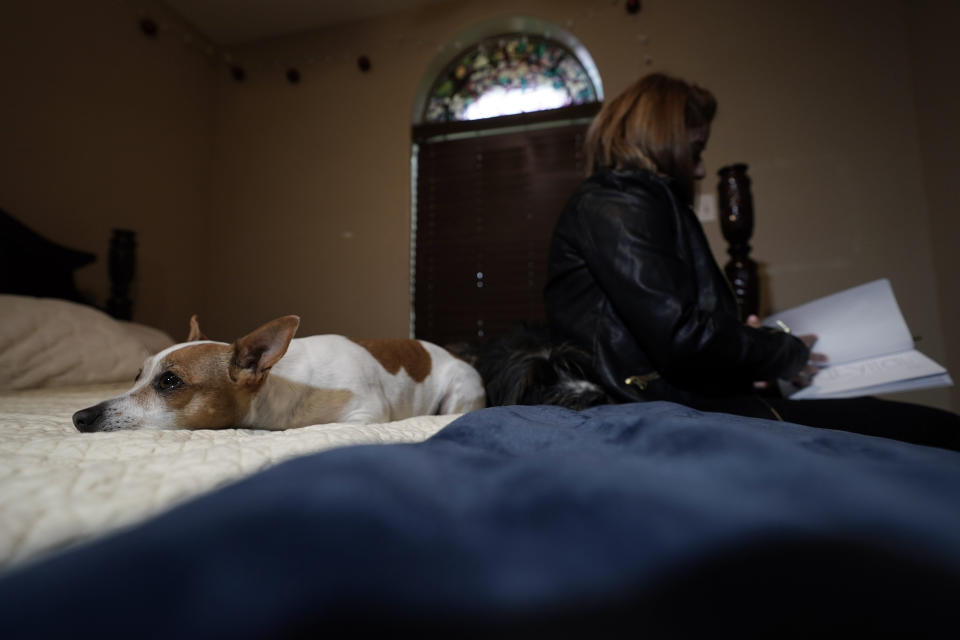 Irma Reyes looks through a scrapbook as she sits on her daughter's bed with dogs Stacy and Georgie, Wednesday, Feb. 1, 2023. Reyes' daughter was one of two teens who men were accused of keeping at a San Antonio motel where other men paid to have sex with them in 2017. Their cases have seen years of delay, a parade of prosecutors, an aborted trial and, ultimately, a stark retreat by the government with the offer of a plea deal. (AP Photo/Eric Gay)