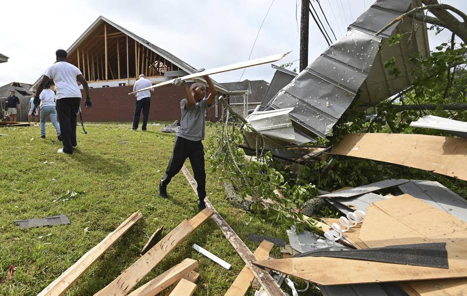 Derrick Pounds Jr. helps his father clean up debris around their house on Elvis Presley Drive in Tupelo, Miss., Monday, May 3, 2021. Multiple tornadoes were reported across the state on Sunday. (AP Photo/Thomas Graning)