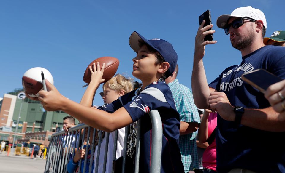 Noah Markovic, 10, of Franklin, Wis. attempts to get autographs from New England Patriots players before the start of a joint practice with the Green Bay Packers on Aug. 16, 2023, in Ashwaubenon, Wis.