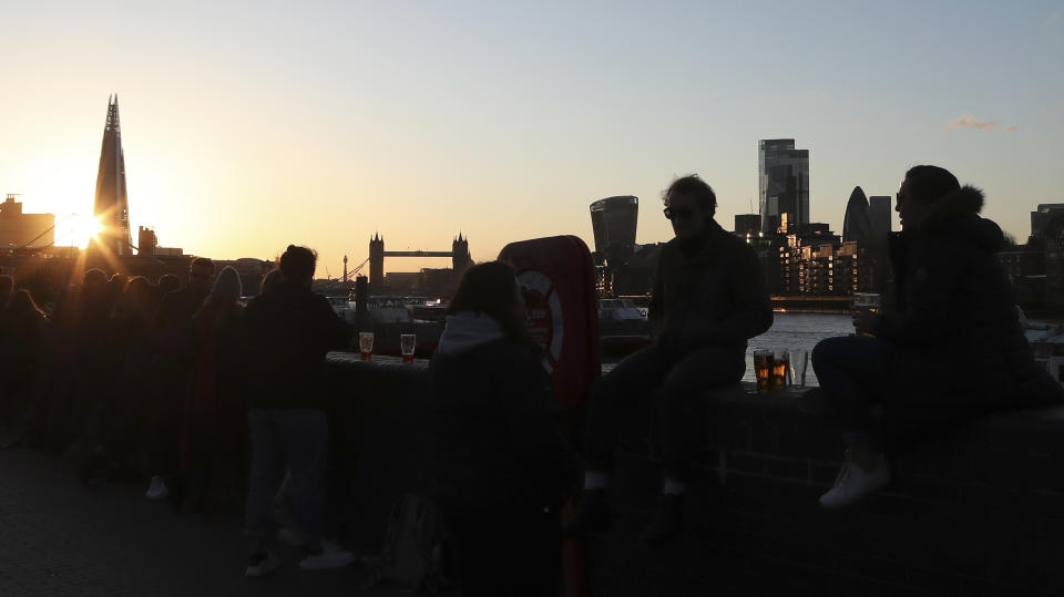 Customers have a drink overlooking the Thames outside the Angel Pub in Rotherhithe, London Wednesday April 14, 2021. The Angel waited until Wednesday to reopen after COVID-19 lockdown restrictions were further eased in parts of the UK on Monday. (AP Photo/Tony Hicks)