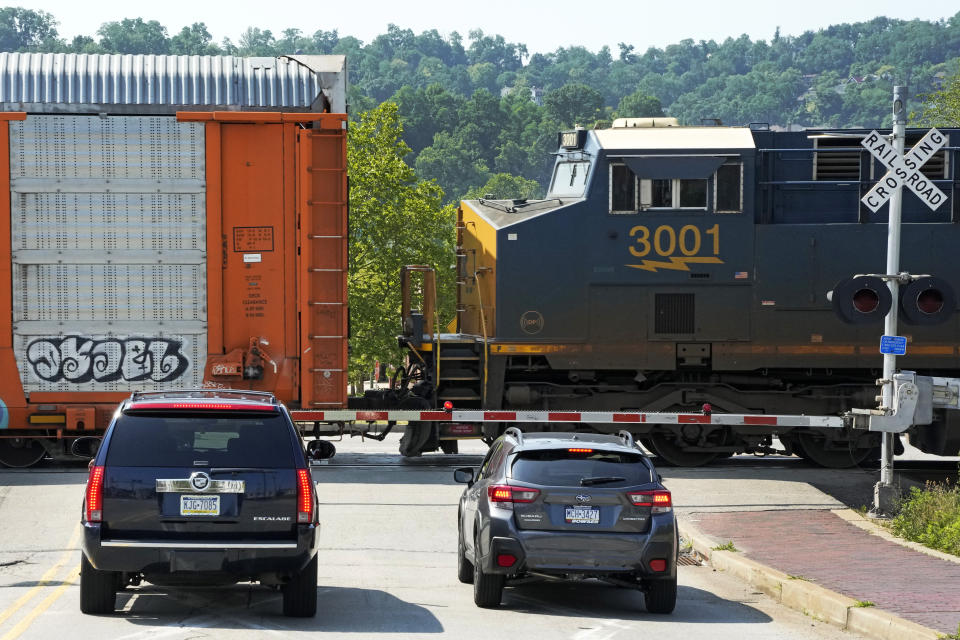 Cars wait at a railroad crossing for a CSX freight train in Homestead, Pa., Sunday, June 18, 2023. Spurred on by train derailments, some states with busy criss-crossing freight railroads are pursuing their own safety remedies rather than wait for federal action amid industry opposition and questions about whether they even have authority to make the changes. (AP Photo/Gene J. Puskar)