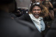 A woman shouts at police officers as residents of Pavao-Pavaozinho slum clash with riot police during a protest against the death of Douglas Rafael da Silva Pereira after his burial in Rio de Janeiro, Brazil, Thursday, April 24, 2014. The protest followed the burial of Douglas Pereira, whose shooting death sparked clashes Tuesday night between police and residents of the Pavao-Pavaozinho slum. (AP Photo/Felipe Dana)