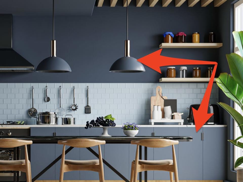 Kitchen with dark-blue walls, lights, and cabinets and a light-blue backsplash with red arrows pointing to cabinets and lights